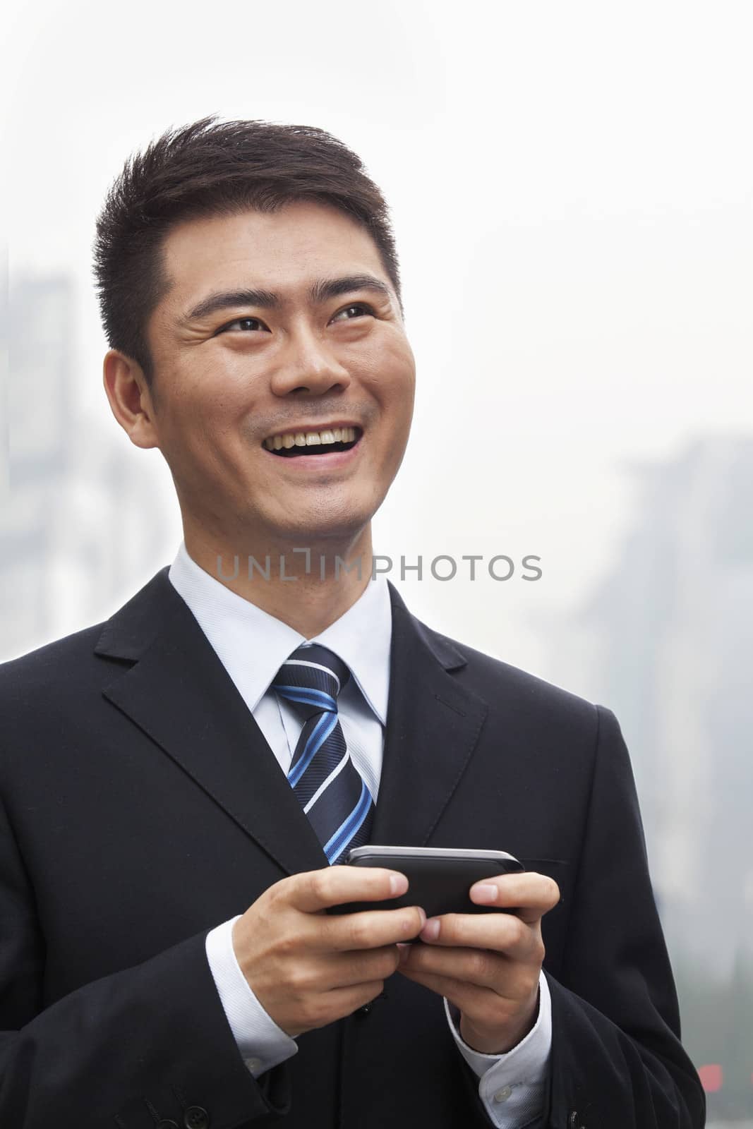 Young Businessman Smiling and Using a Smart Phone by XiXinXing