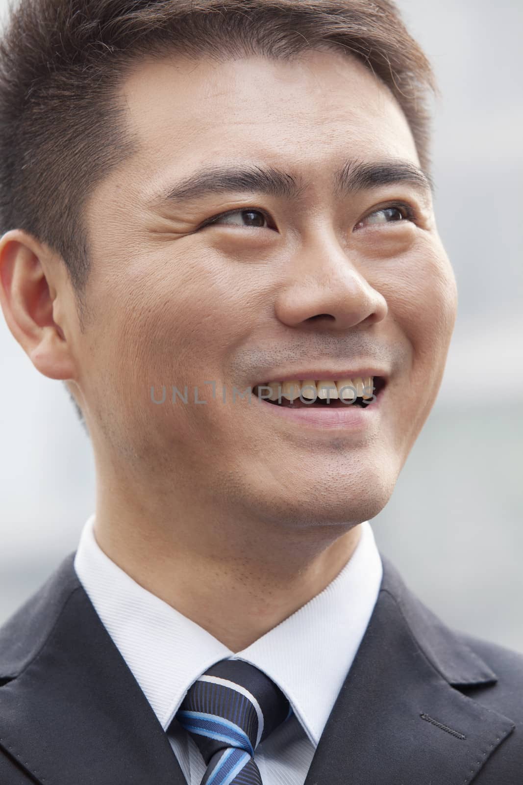 Young Businessman Smiling and Looking Away, Portrait by XiXinXing