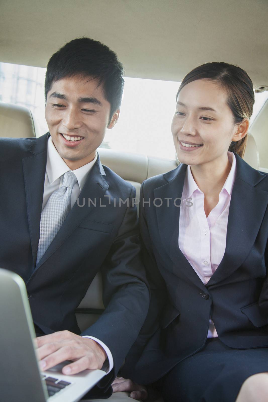 Business Colleagues Using Laptop in Back Seat Of Car