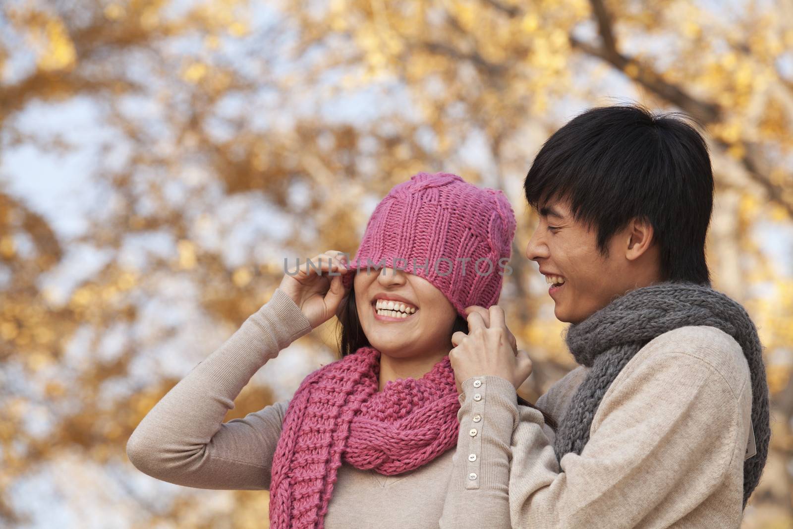 Young Man Covering a Young Woman's Eyes with Hat
