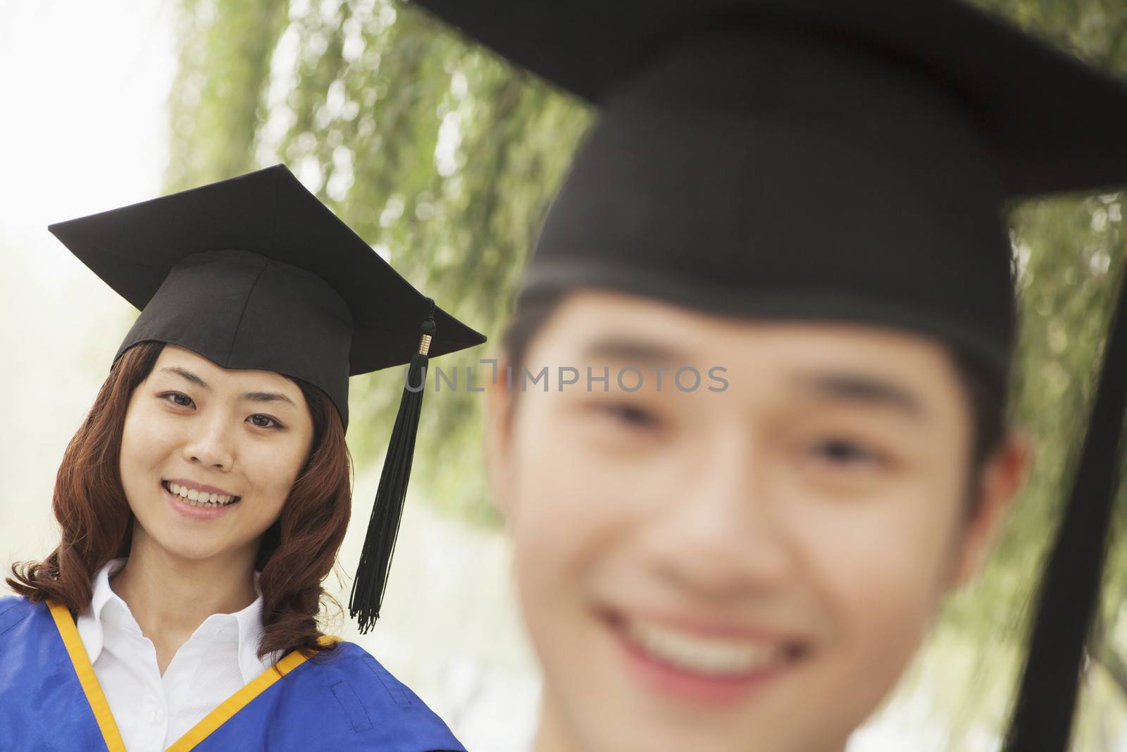 Two Young University Graduates Looking At The Camera, Man in Front