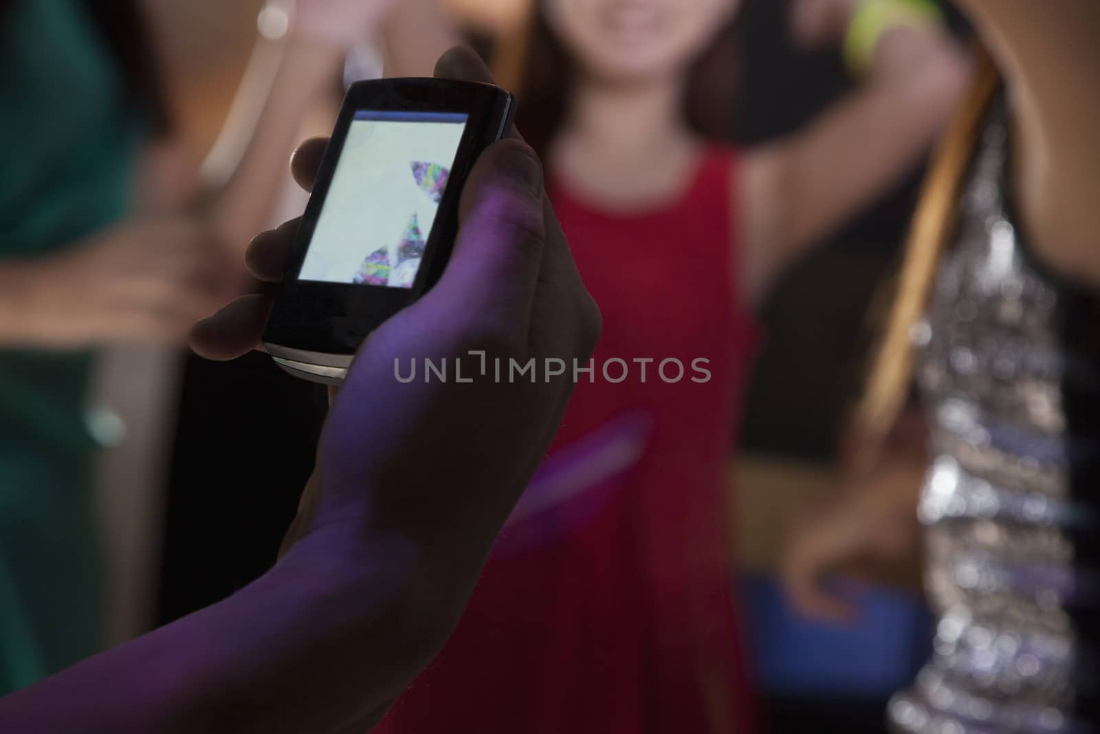 A young man uses a mobile phone in nightclub