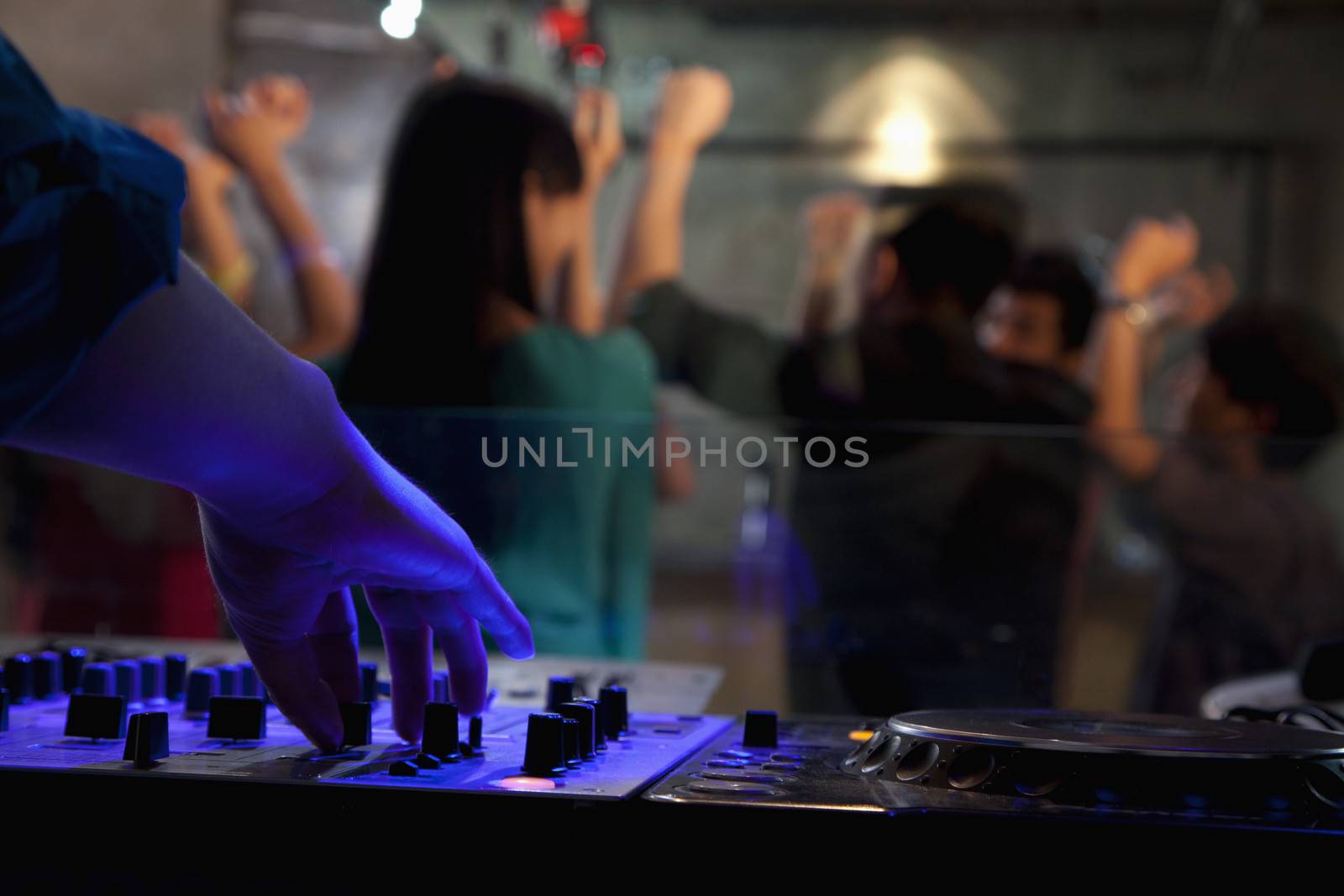 A view from DJ's deck of a crowd dancing in nightclub, 