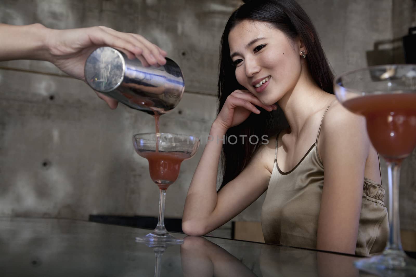 Bartender serving a cocktail to a young woman