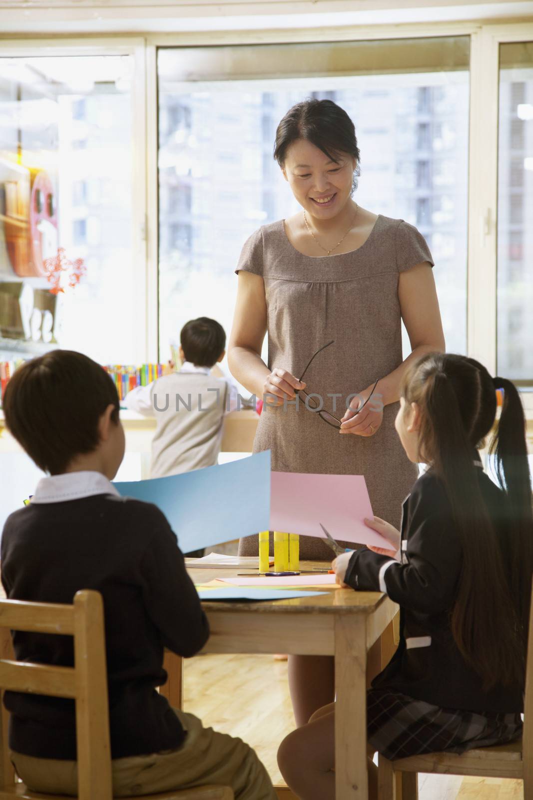 Teacher talking to students doing art in classroom  by XiXinXing