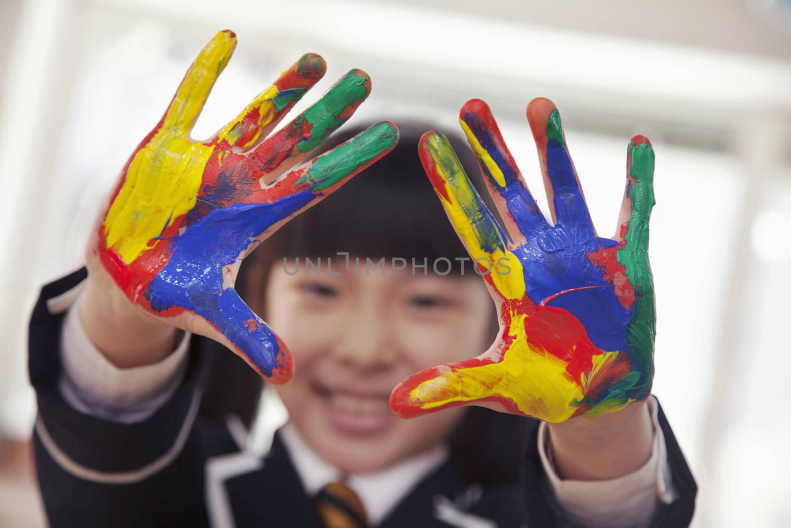 Smiling schoolgirl finger painting, close up on hands