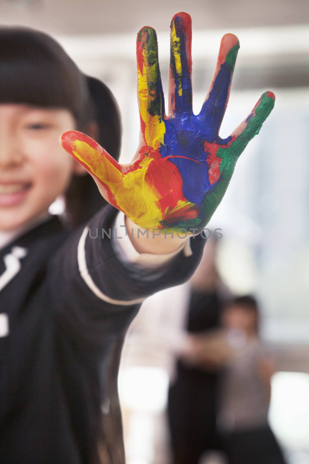 Smiling schoolgirl finger painting, close up on hand