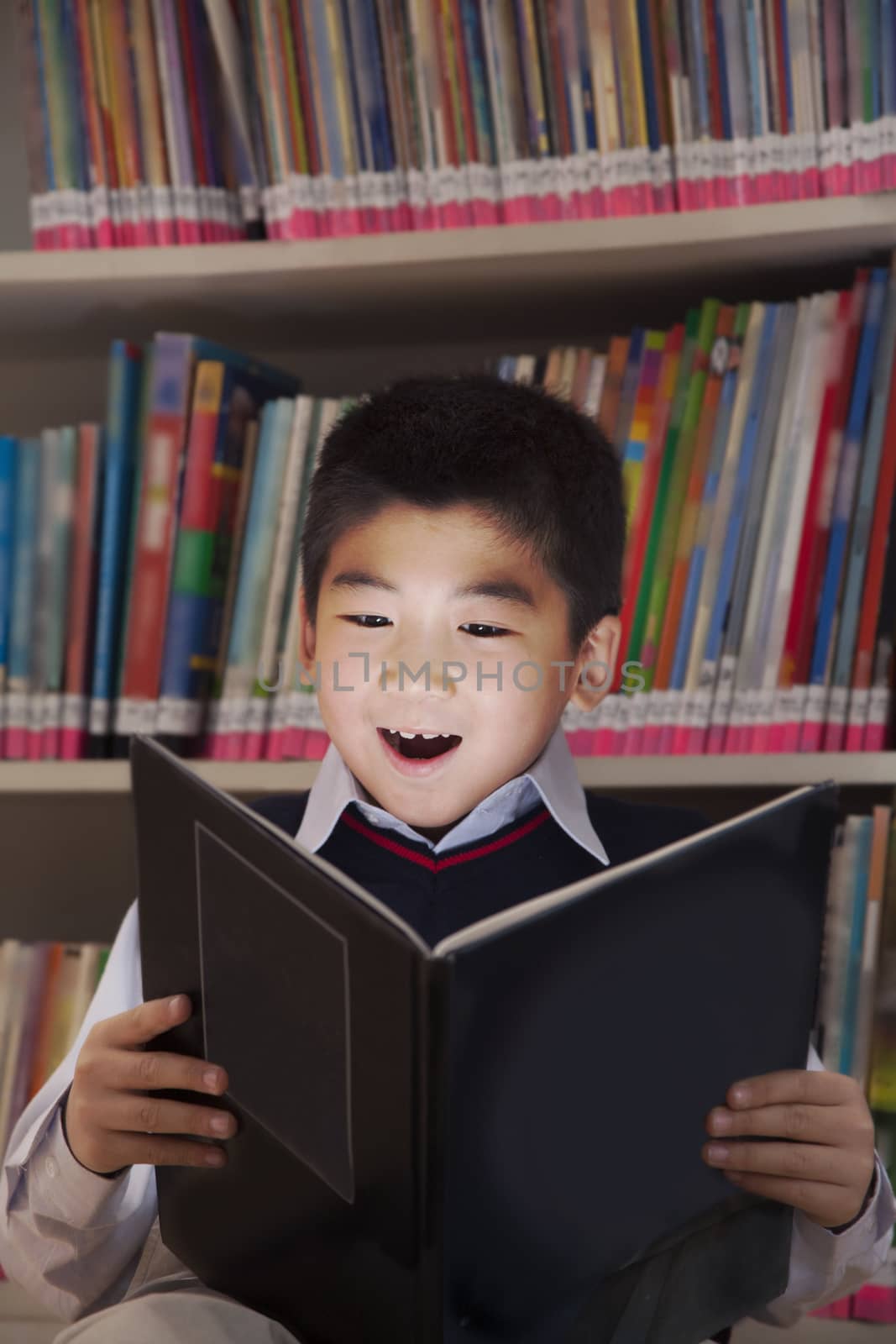 Schoolboy reading a book with her face lit up 