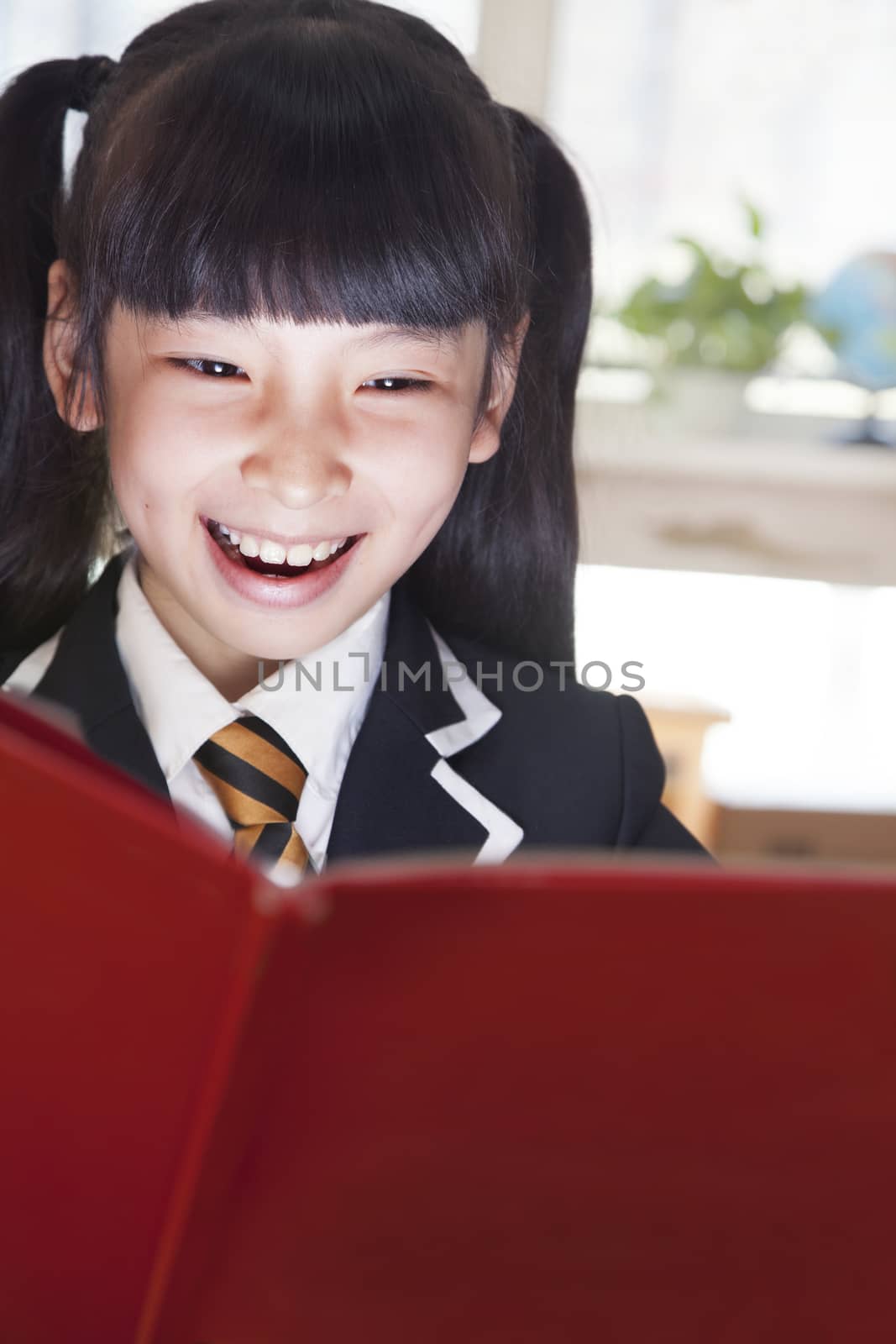 Schoolgirl reading a book with her face lit up 