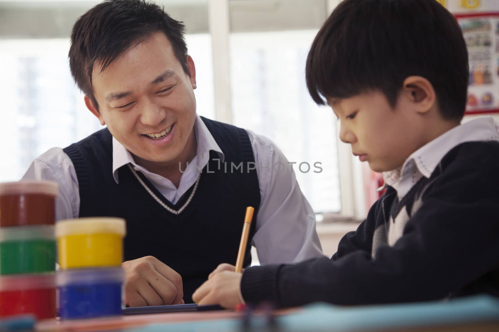 Teacher helping schoolboy with arts and crafts, Beijing