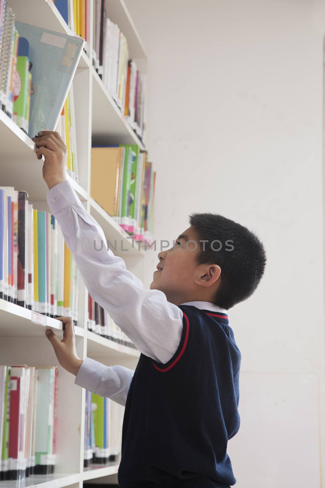 Schoolboy reaching for book off bookshelf by XiXinXing