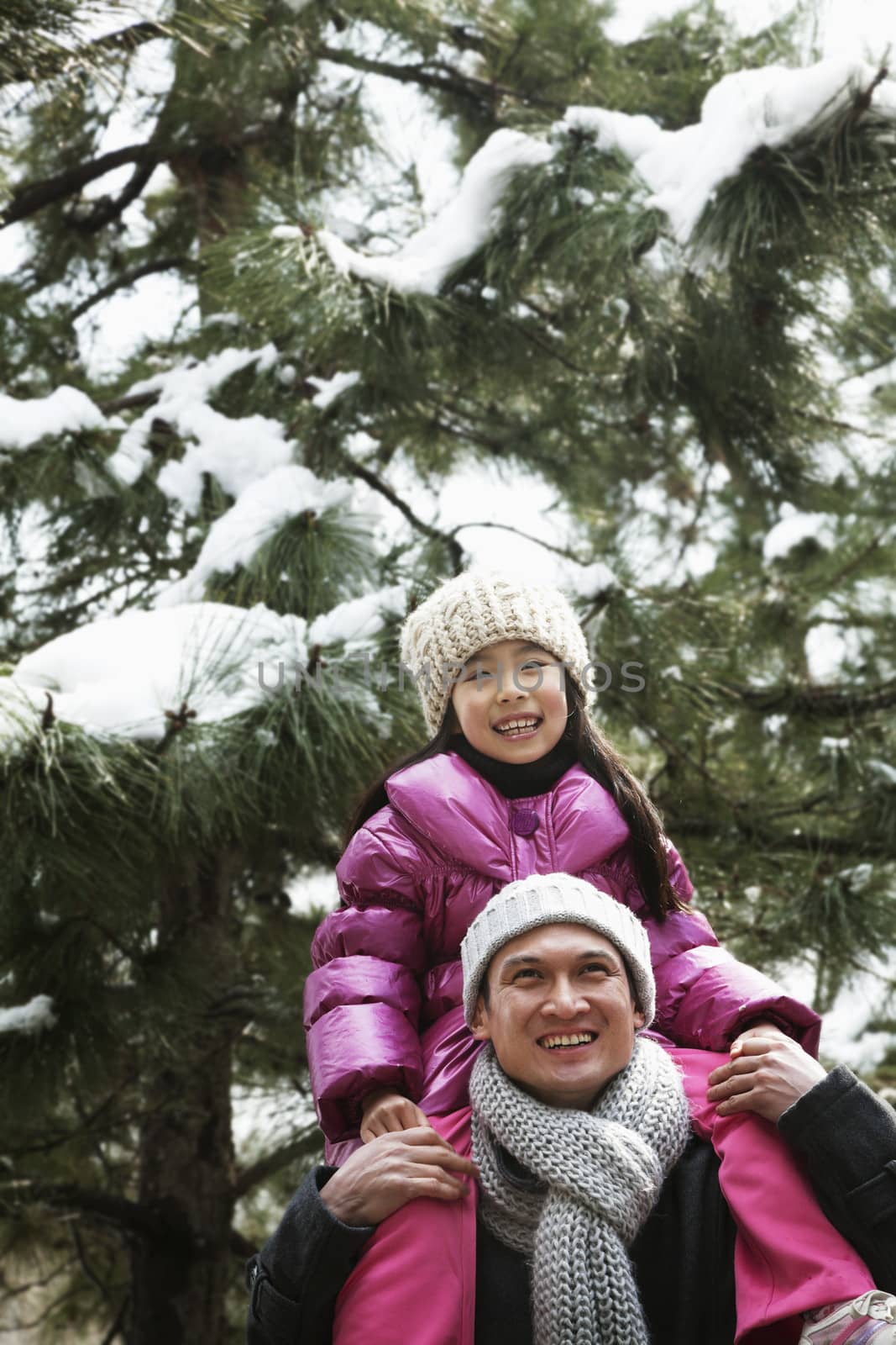 Father and daughter under tree covered in snow by XiXinXing