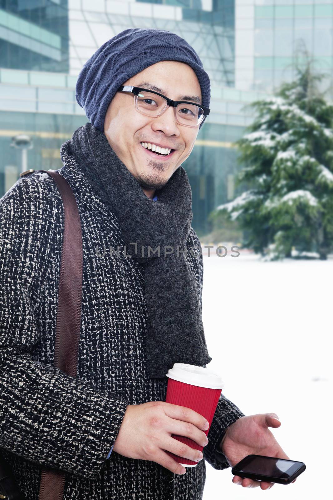 Man in winter clothes holding coffee cup and mobile phone