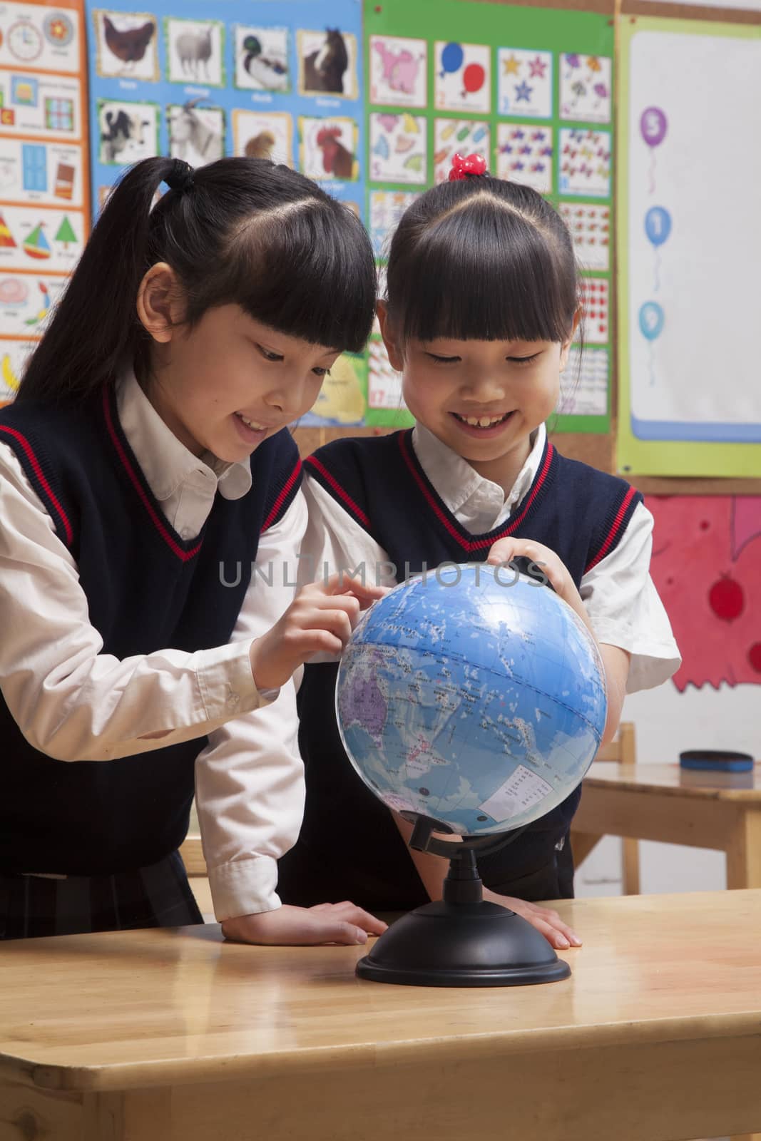 Schoolgirls looking at a globe in the classroom