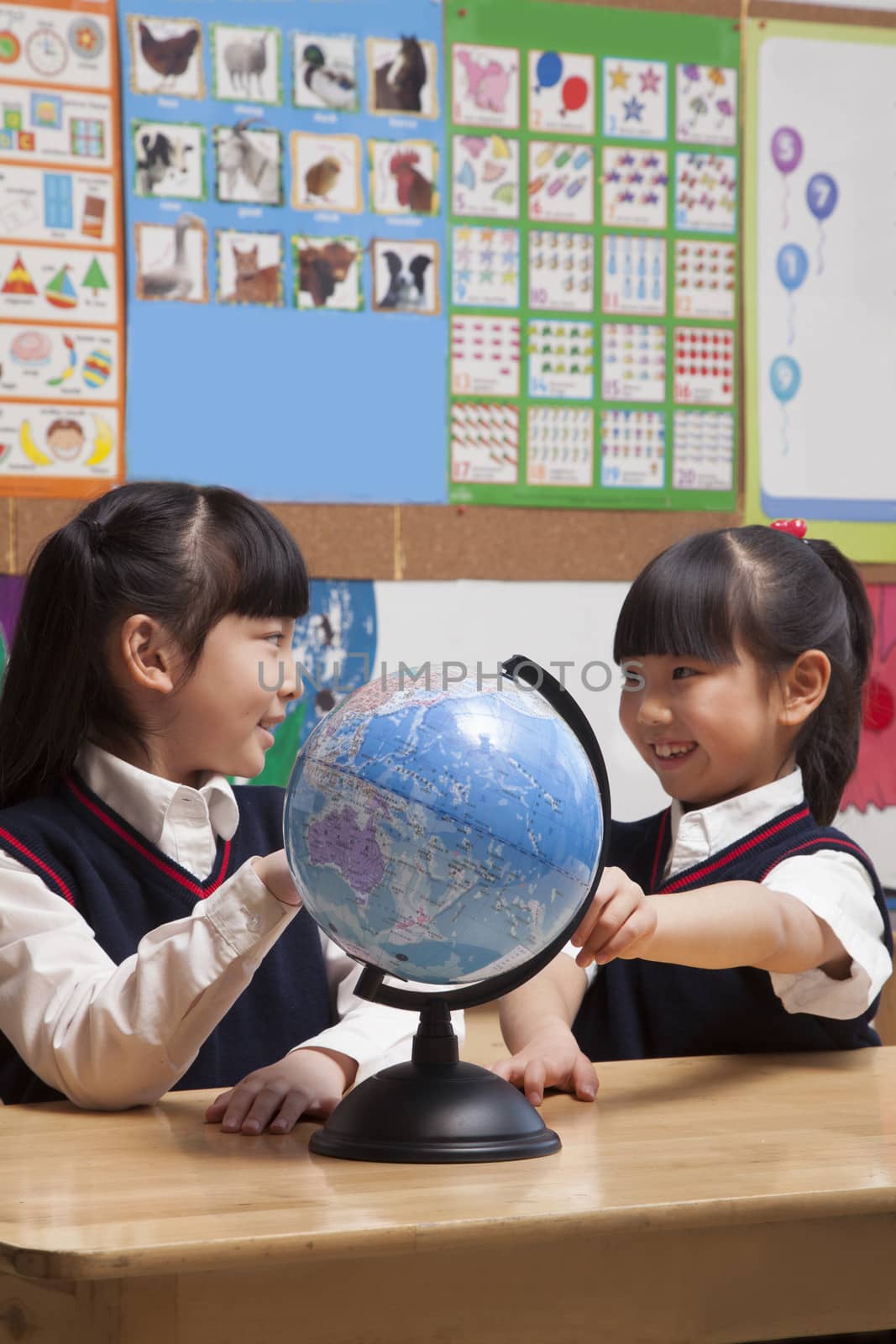 Schoolgirls looking at a globe in the classroom