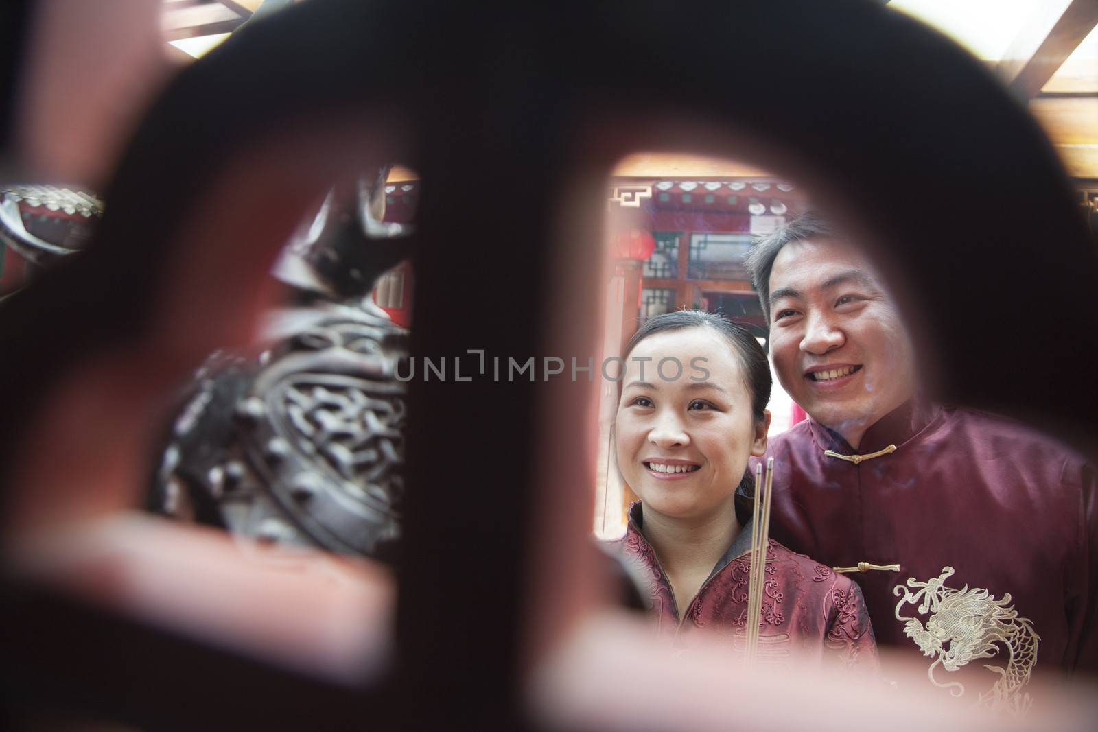 Couple holding offering incense at the temple in traditional clothing