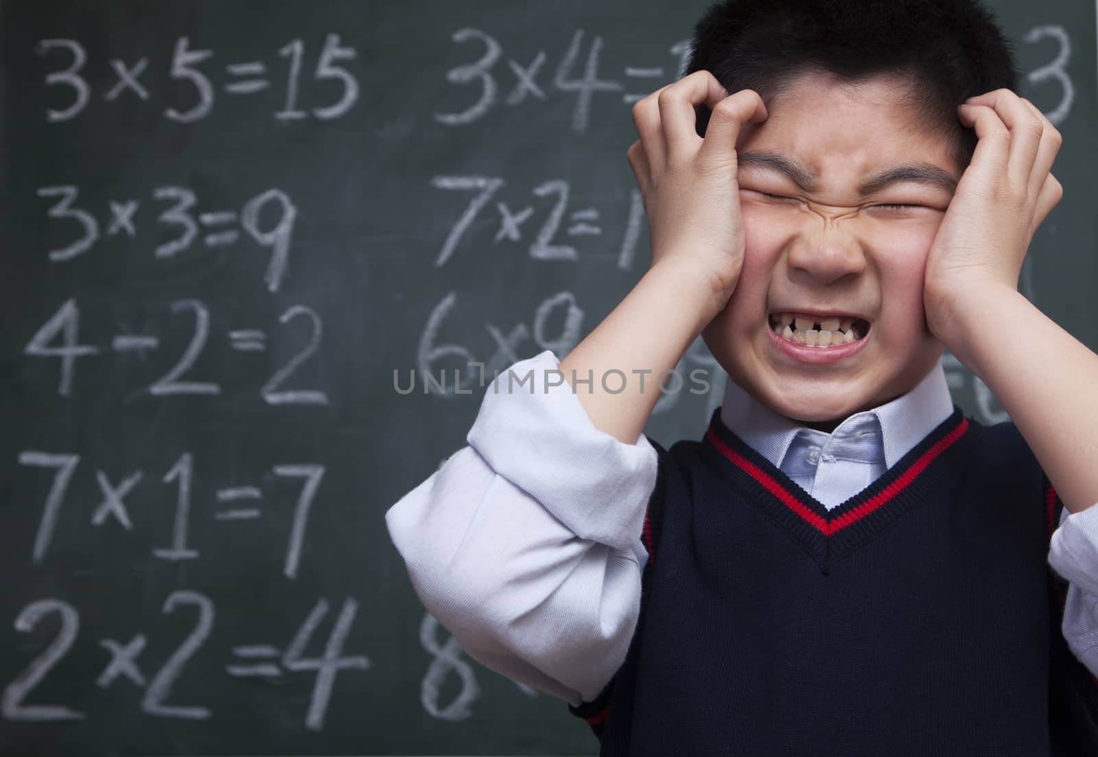 Schoolboy in front of blackboard with head in his hands