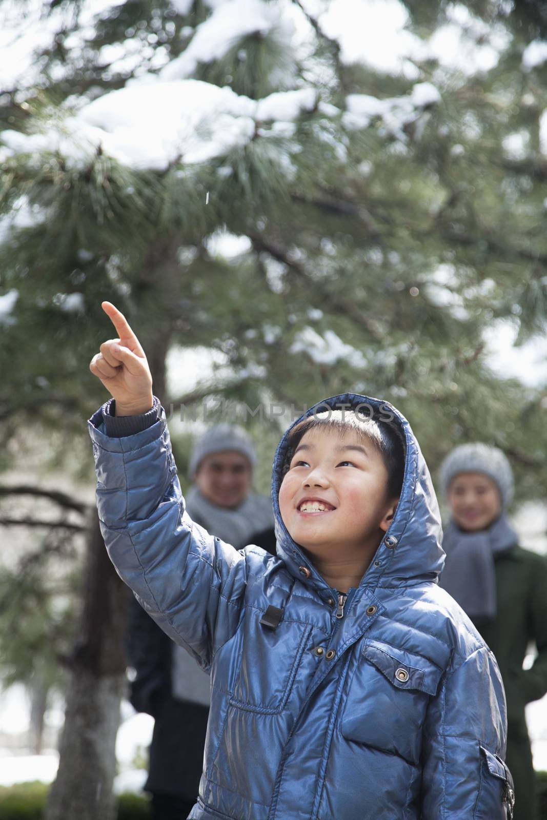 Boy pointing up with parents on the background
