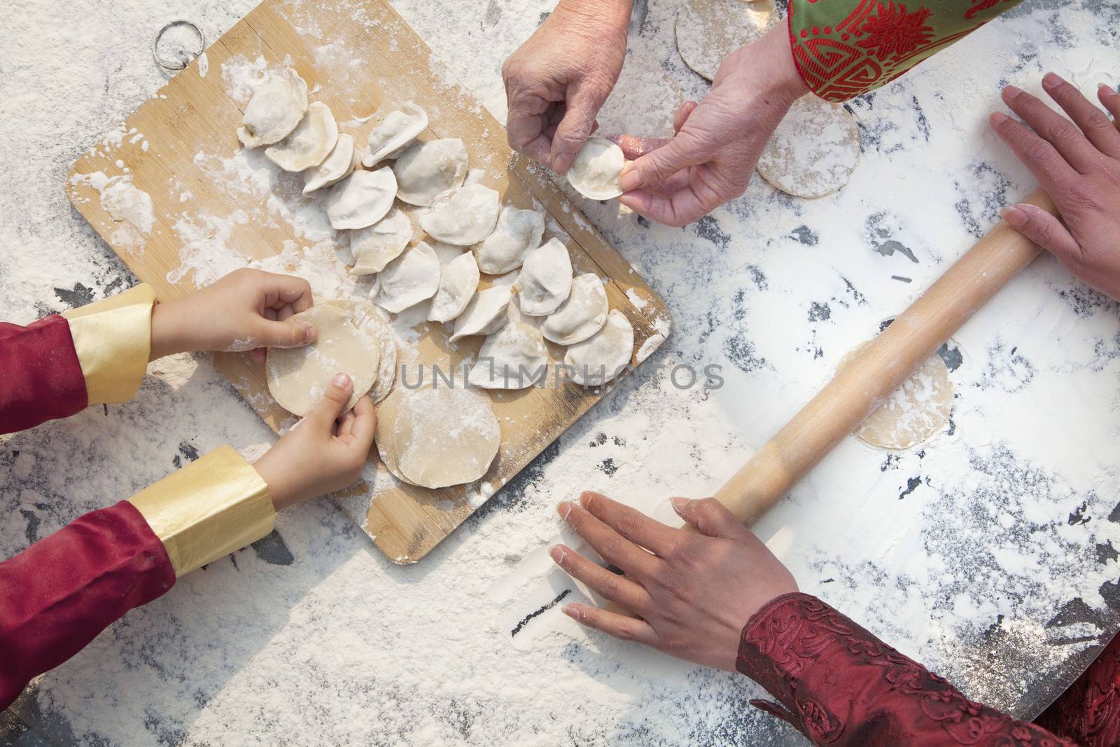 Three generation of women making dumplings, hands only