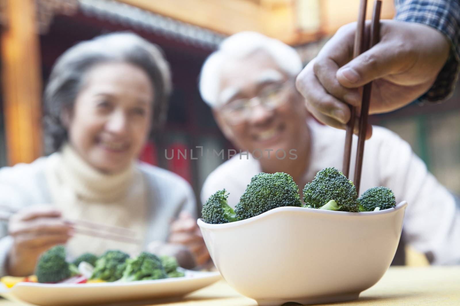 Close up of hand picking up broccoli with chopsticks 