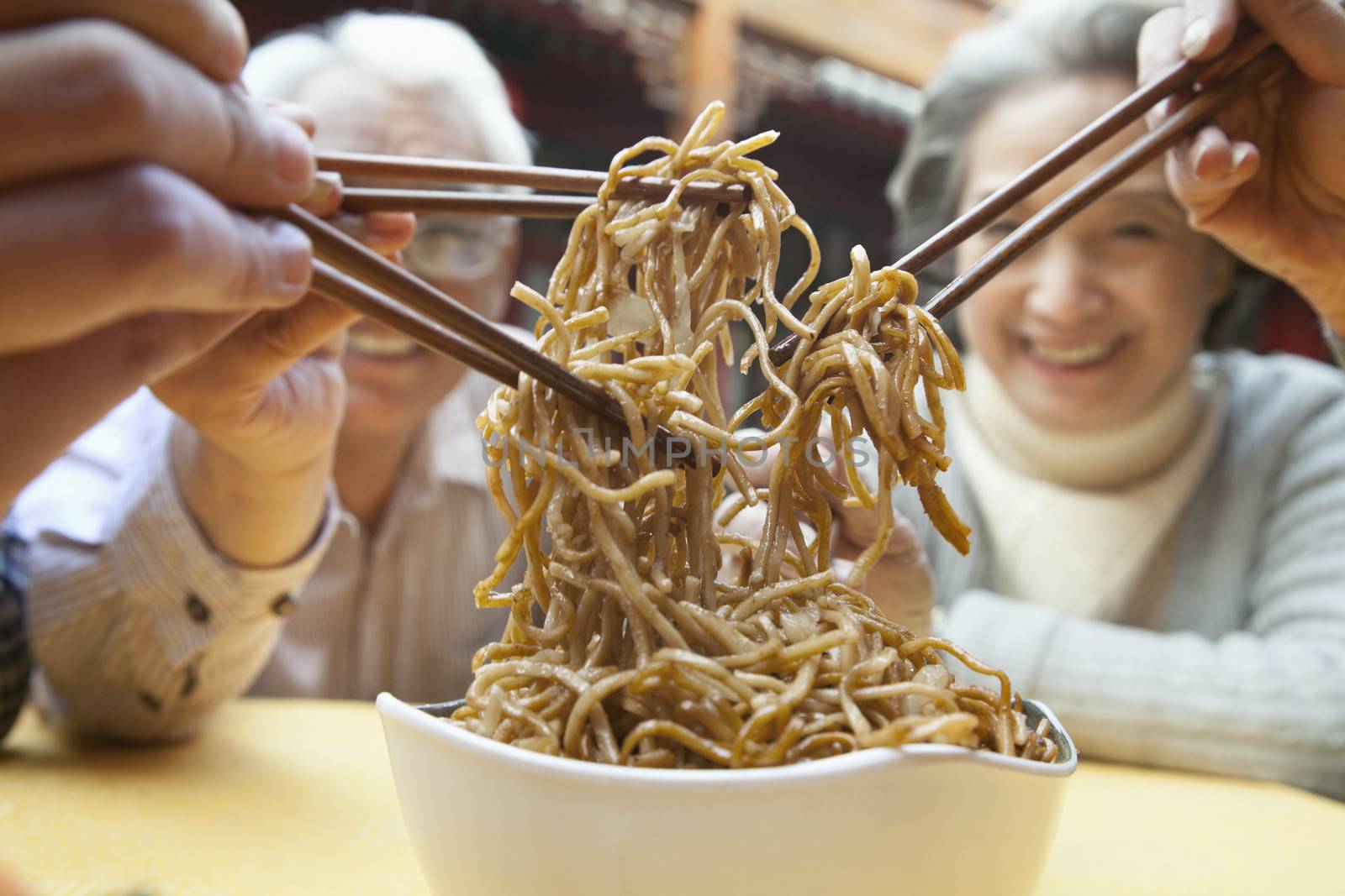 People sharing noodles, close-up