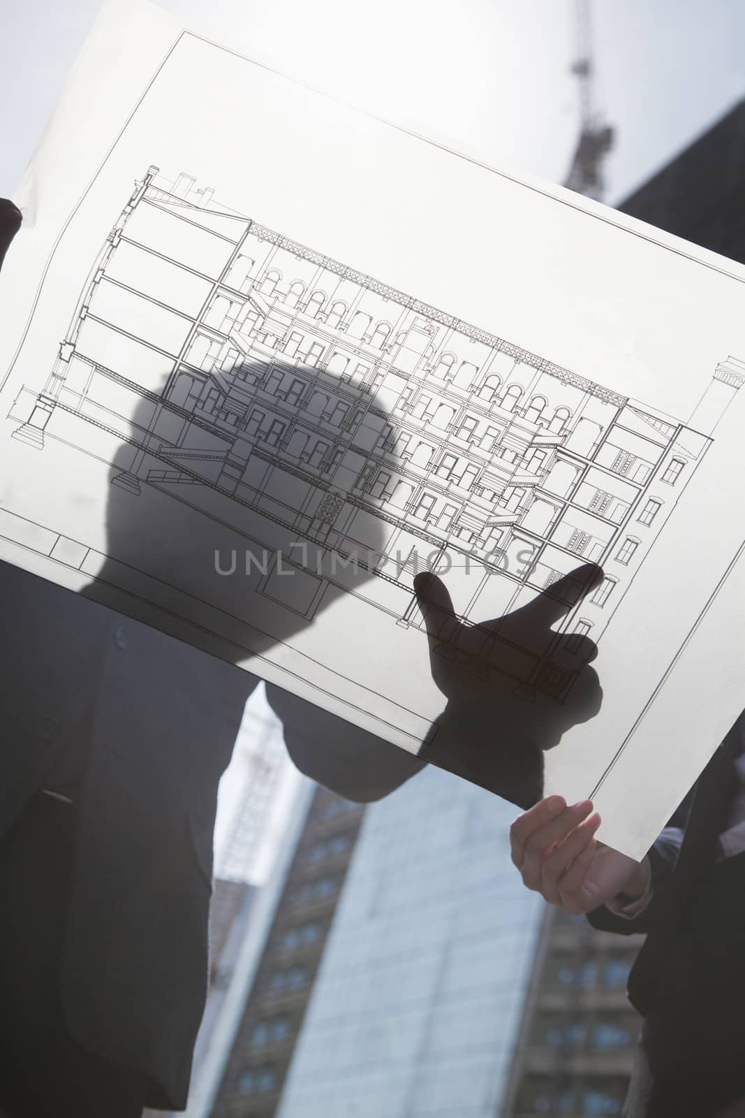 Two architects looking at blueprint on construction site