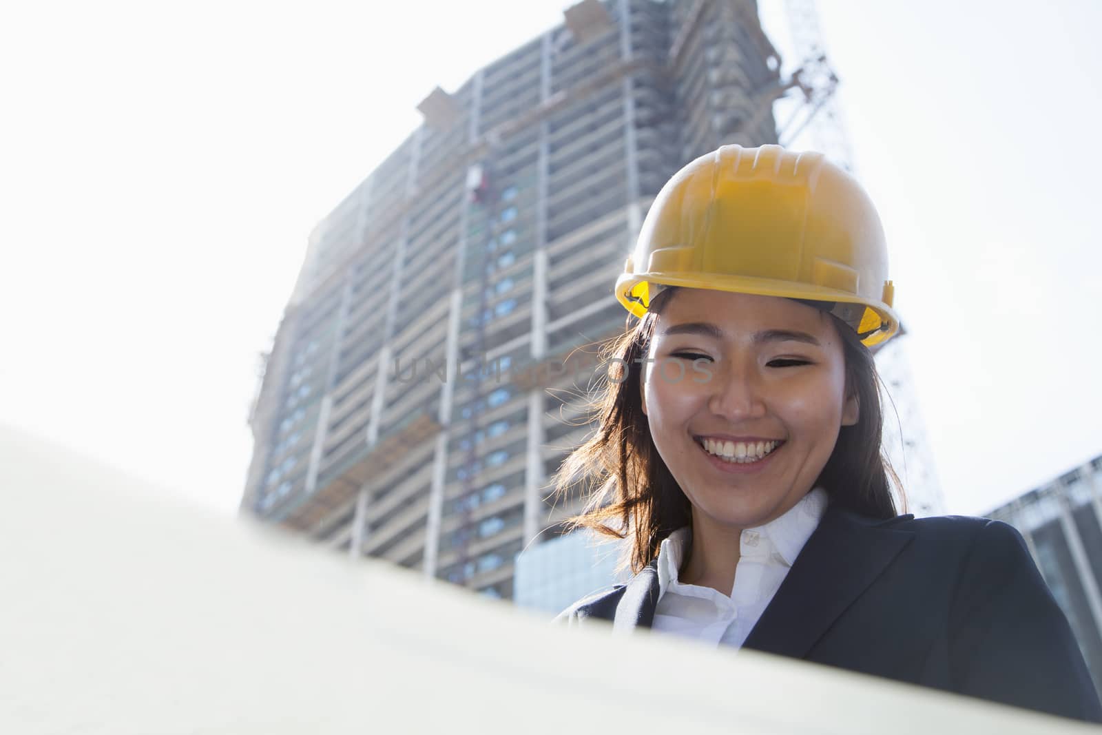 Young architect looking down at blueprint outdoors