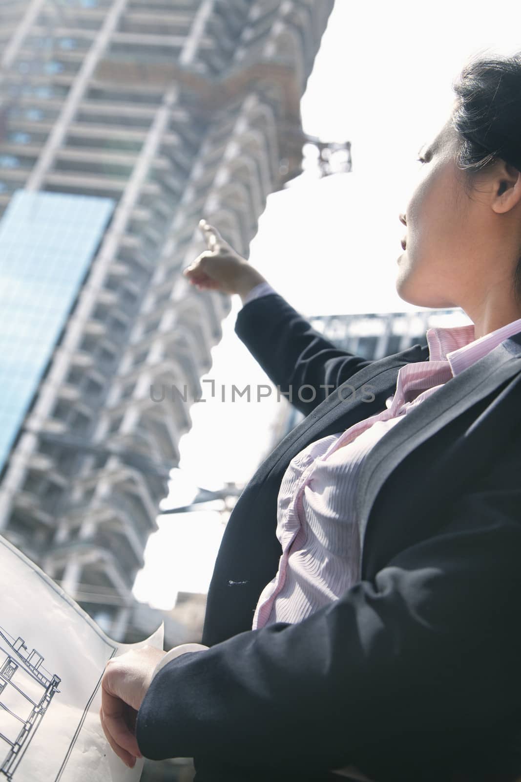 Architect pointing at building at a construction site by XiXinXing