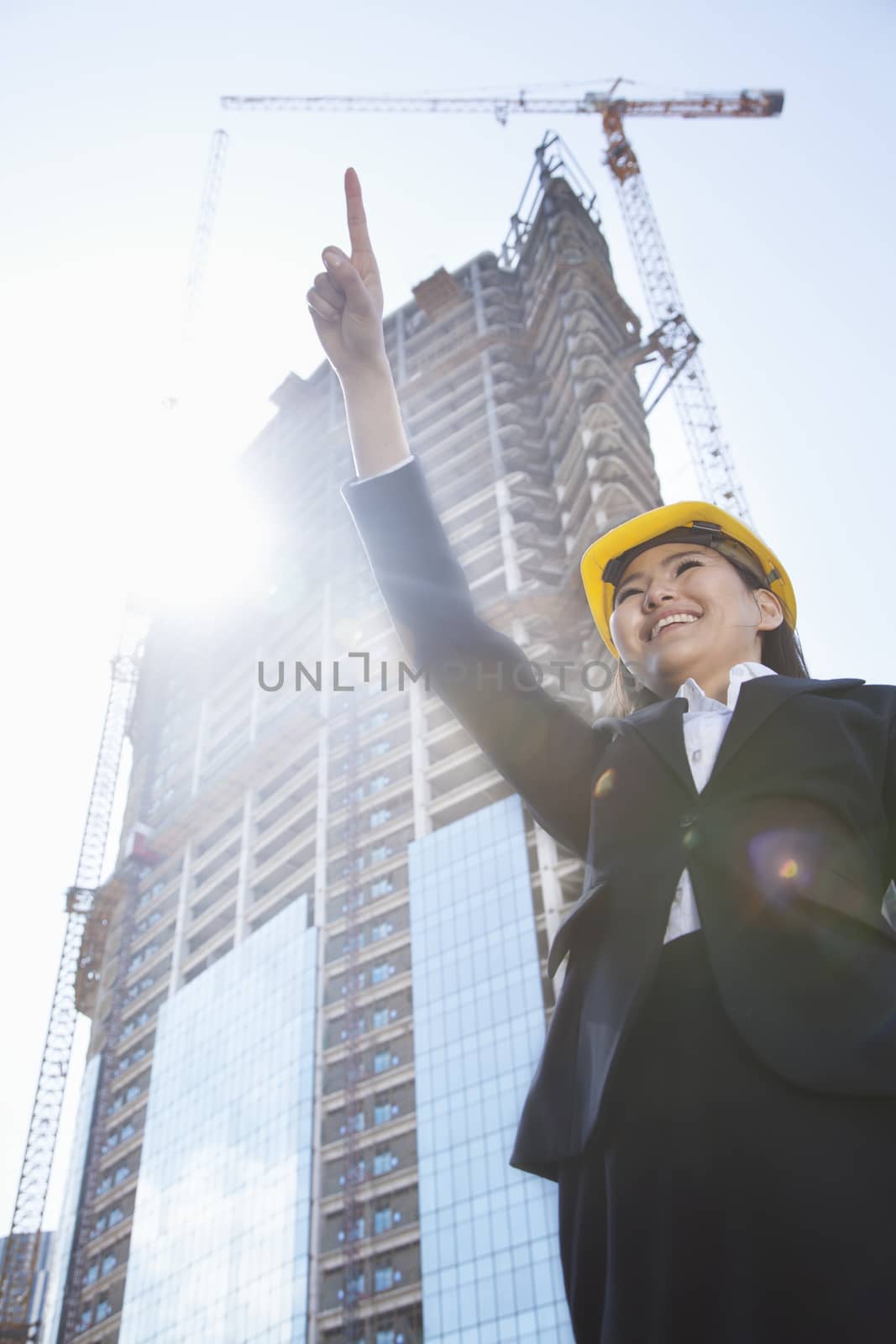 Young female architect pointing at a construction site
