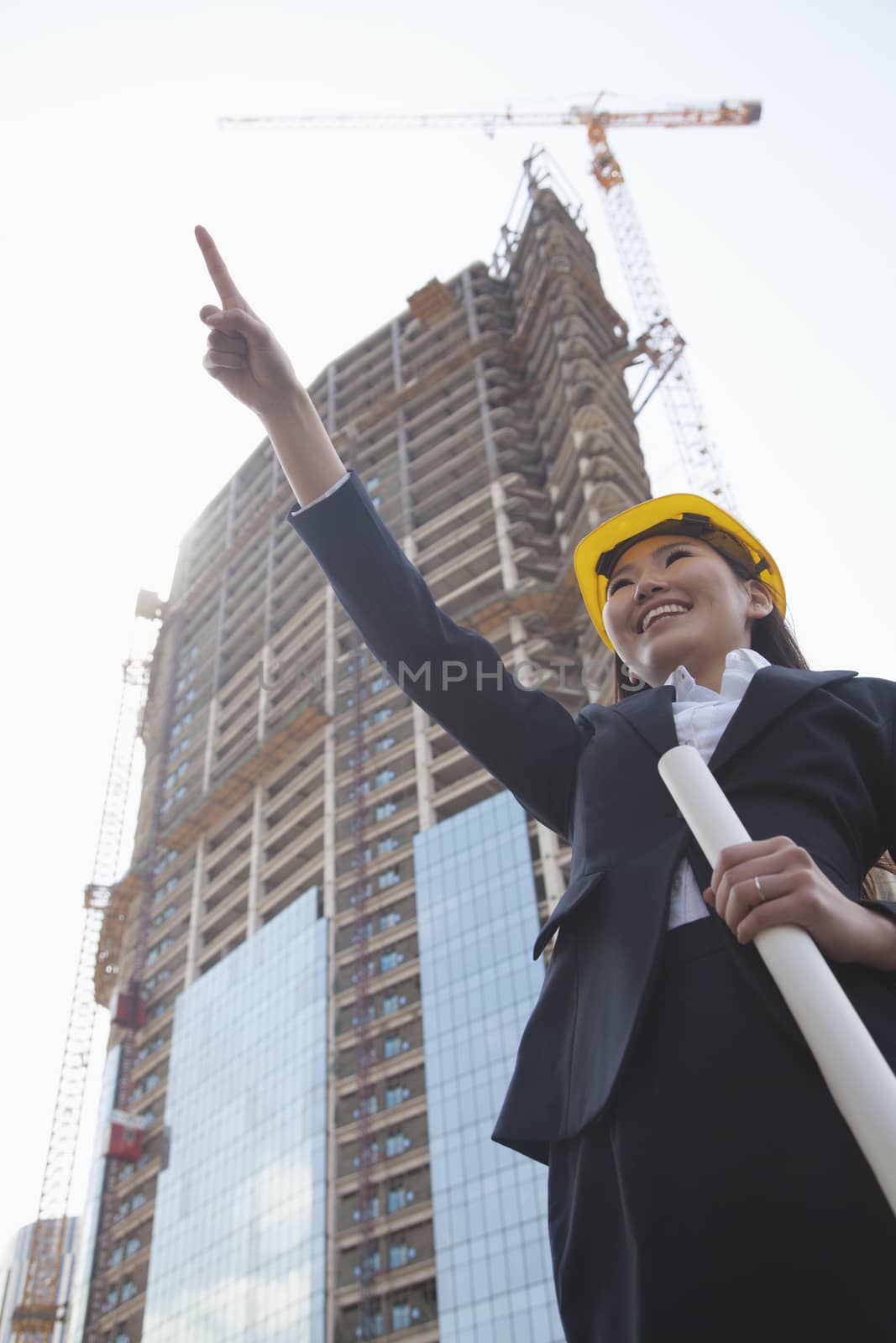 Young female architect pointing at a construction site by XiXinXing