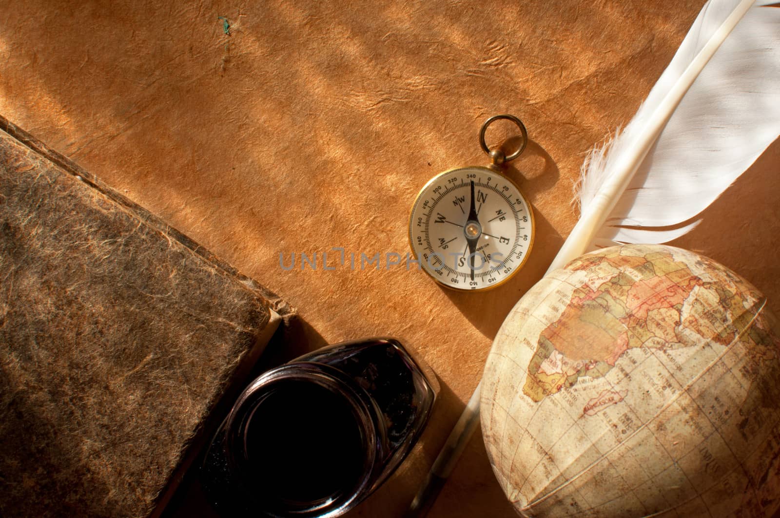 Still life background consisting of vintage objects including a quill and compass on an old paper background