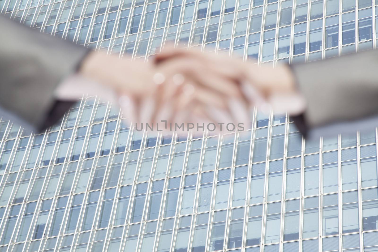 Close up of two business people shaking hands by Chinas world trade center in Beijing by XiXinXing