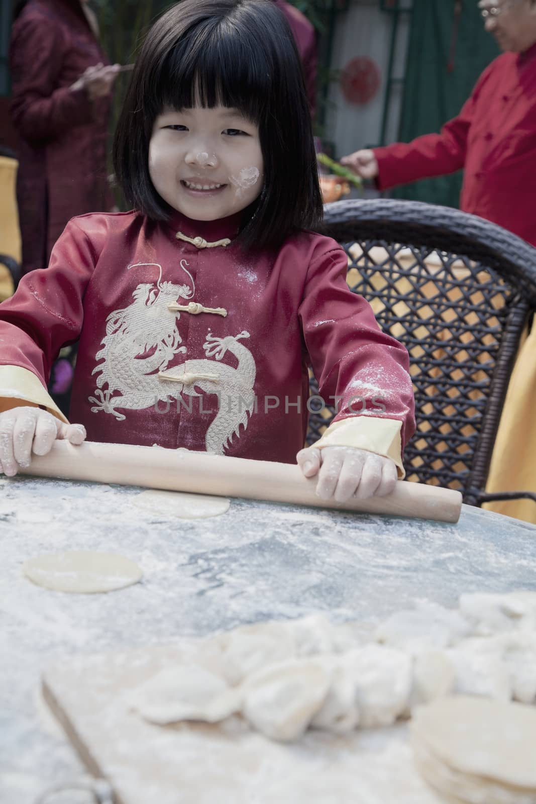 Portrait of little girl making dumplings in traditional clothing