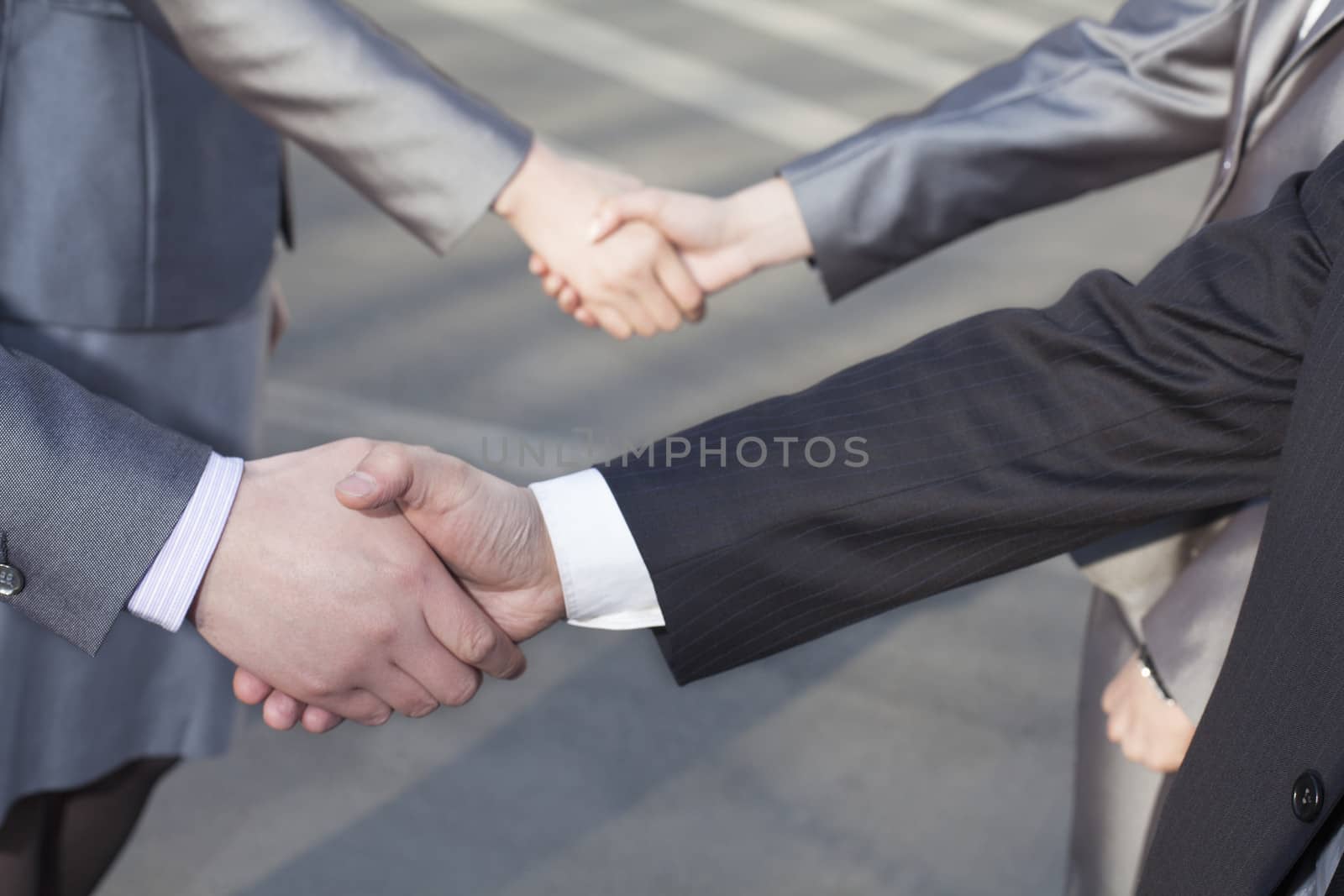 Close up of four business people shaking hands by XiXinXing