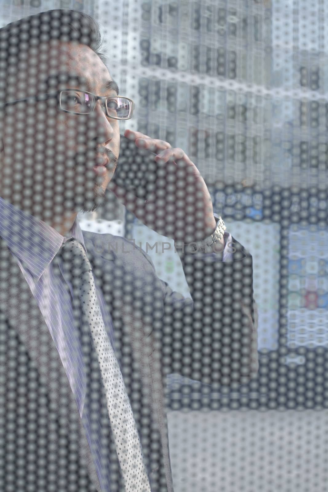 Businessman on the phone on other side of glass wall by XiXinXing