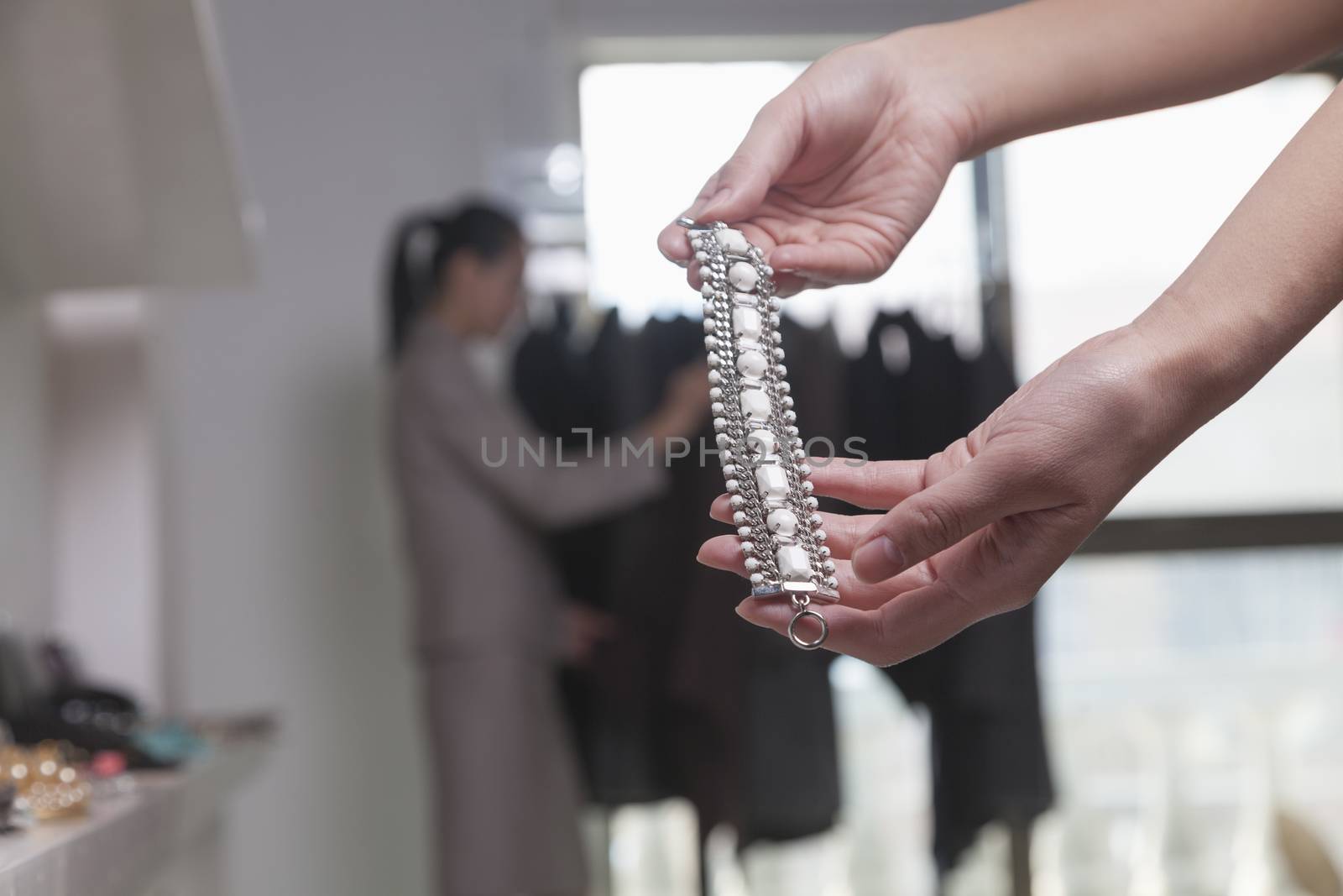 Woman holding piece of jewelry at store, close-up by XiXinXing