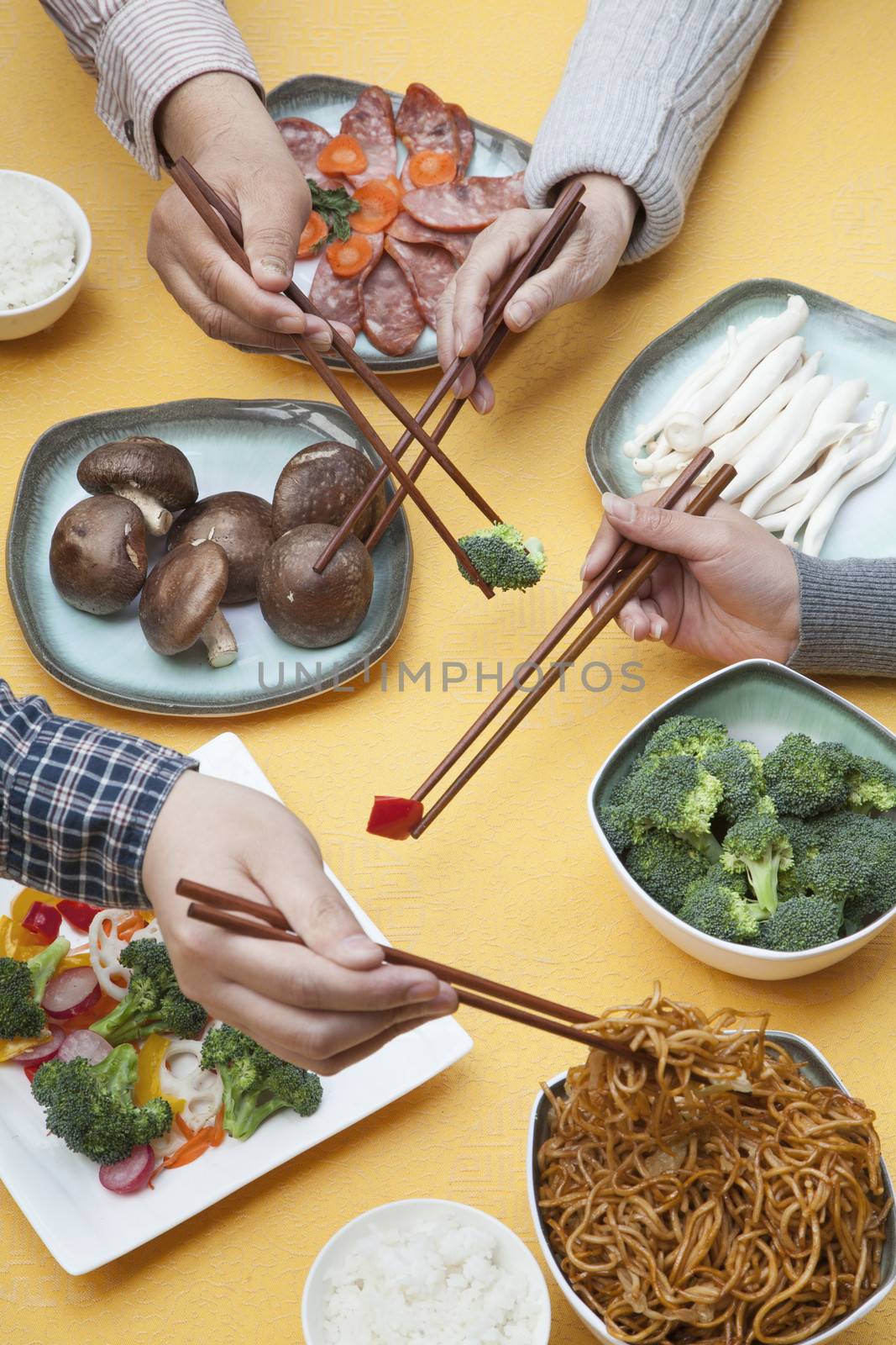 Close up of people using chopsticks with Chinese food by XiXinXing