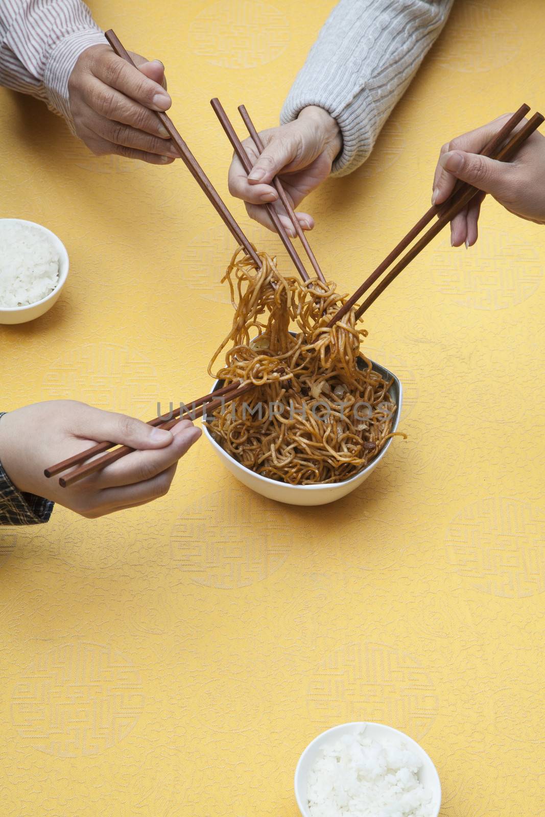 Close up of people holding chopsticks and sharing one dish by XiXinXing