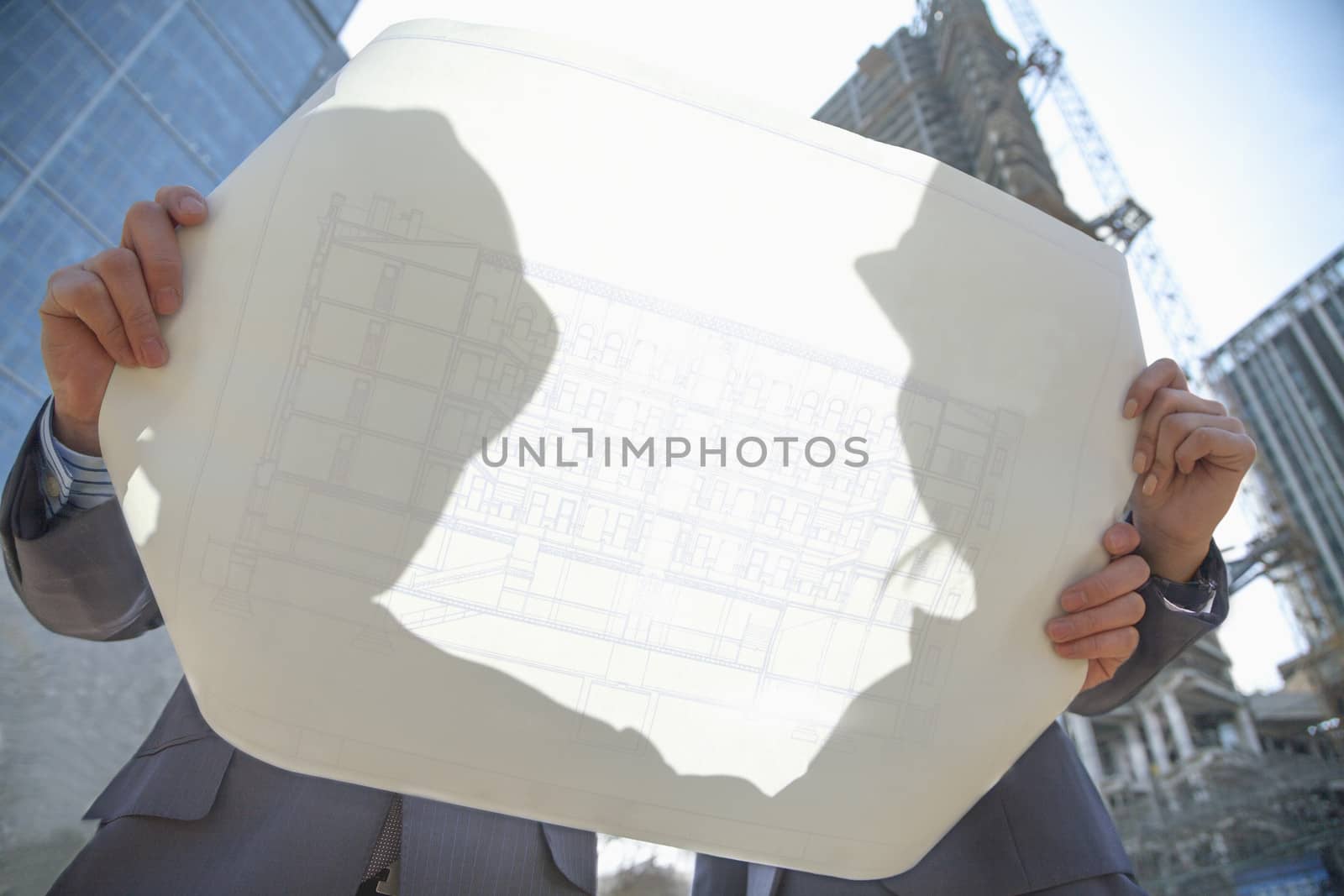 Two architects at a construction site holding blueprint by XiXinXing