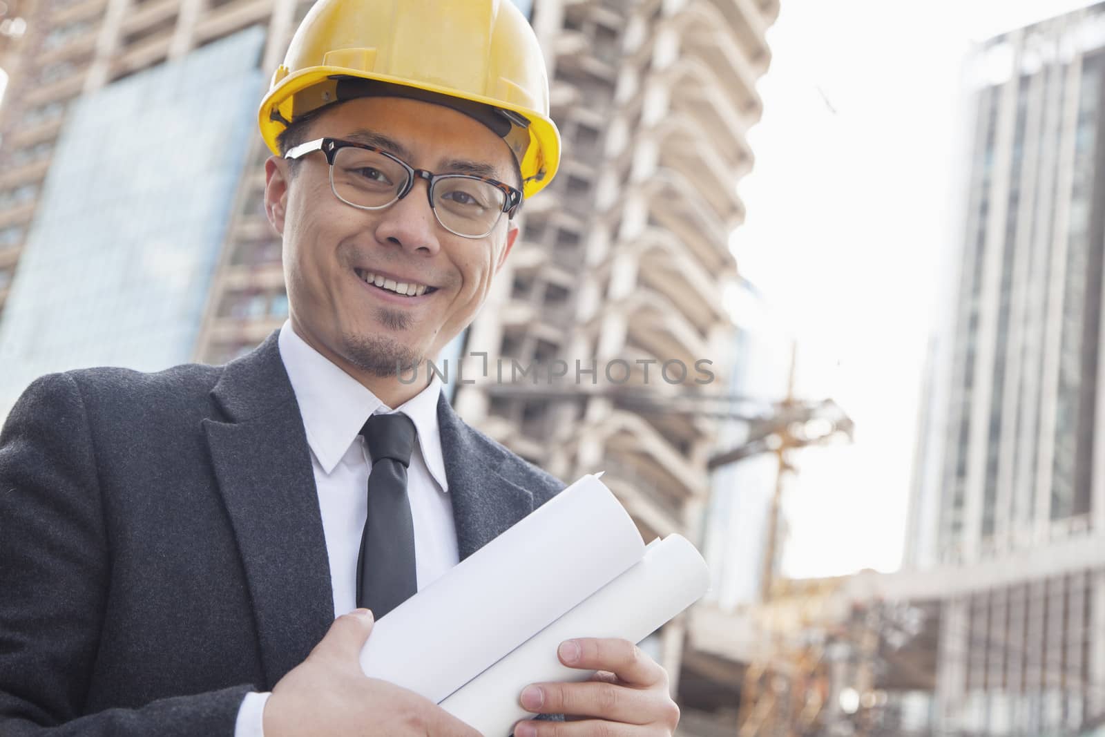 Portrait of male architect on site carrying blueprints by XiXinXing