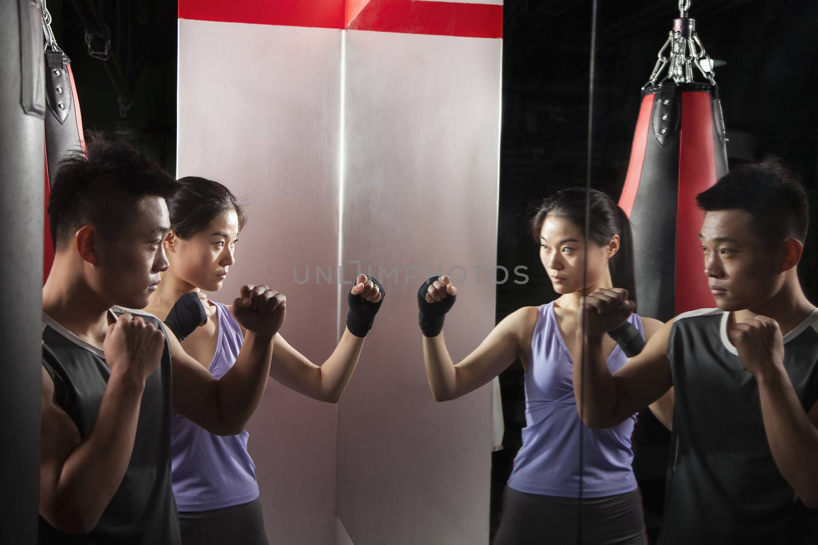 Boxing Instructor and female student practicing stance in front of the mirror at the boxing gym