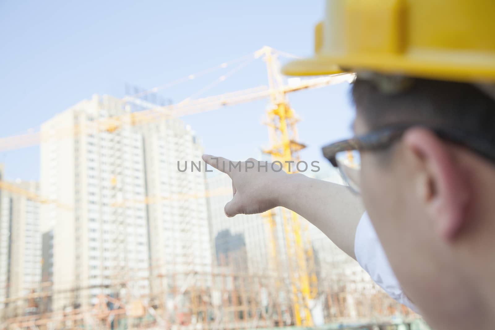 Architect on a construction site pointing at a skyscraper by XiXinXing