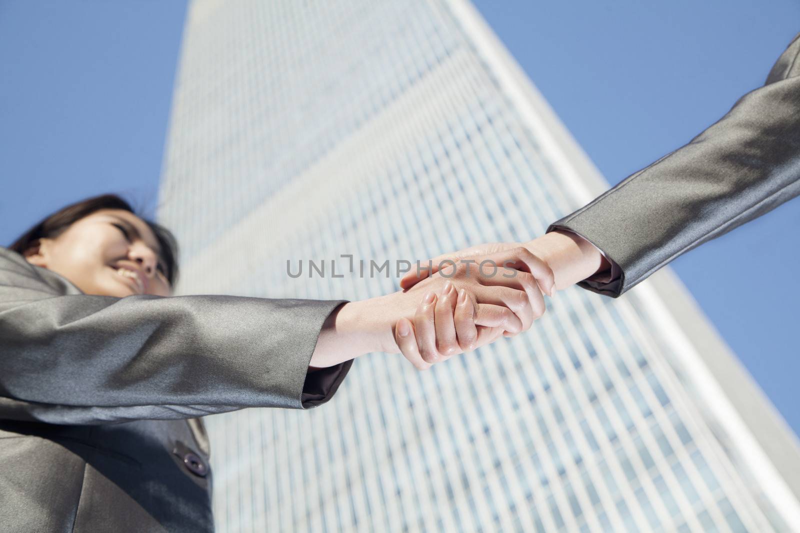 Close up of two business people shaking hands by the china world trade center in Beijing