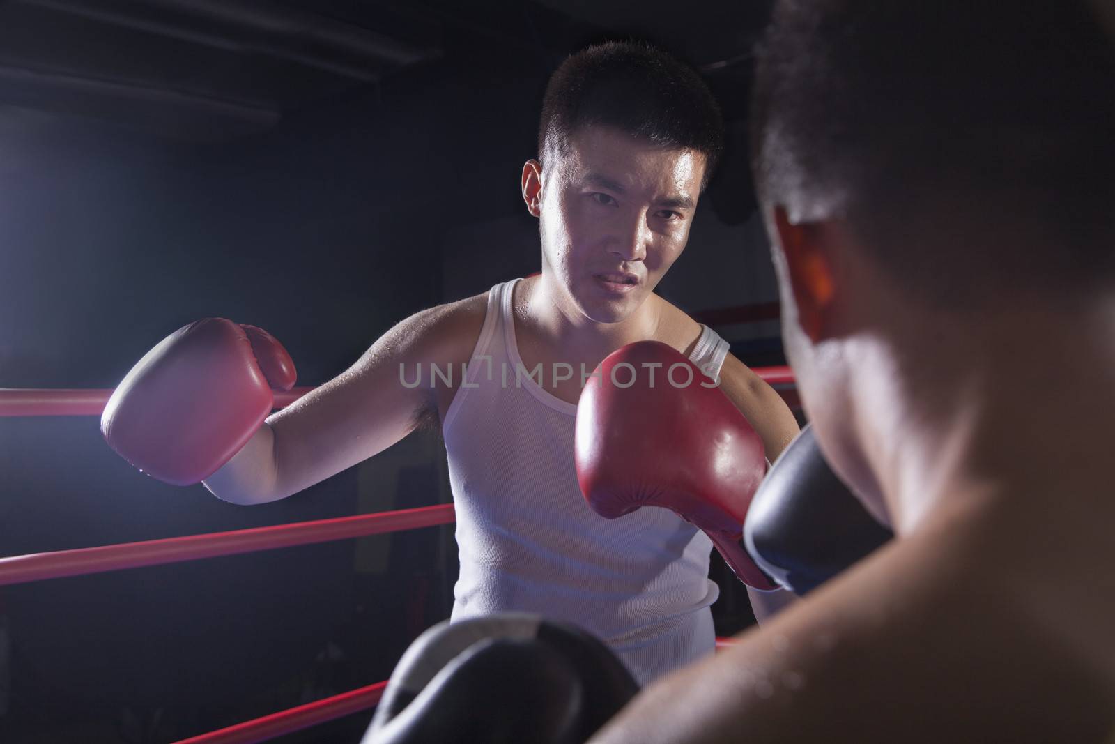 Over the shoulder view of two male boxers fighting in the boxing ring in Beijing, China