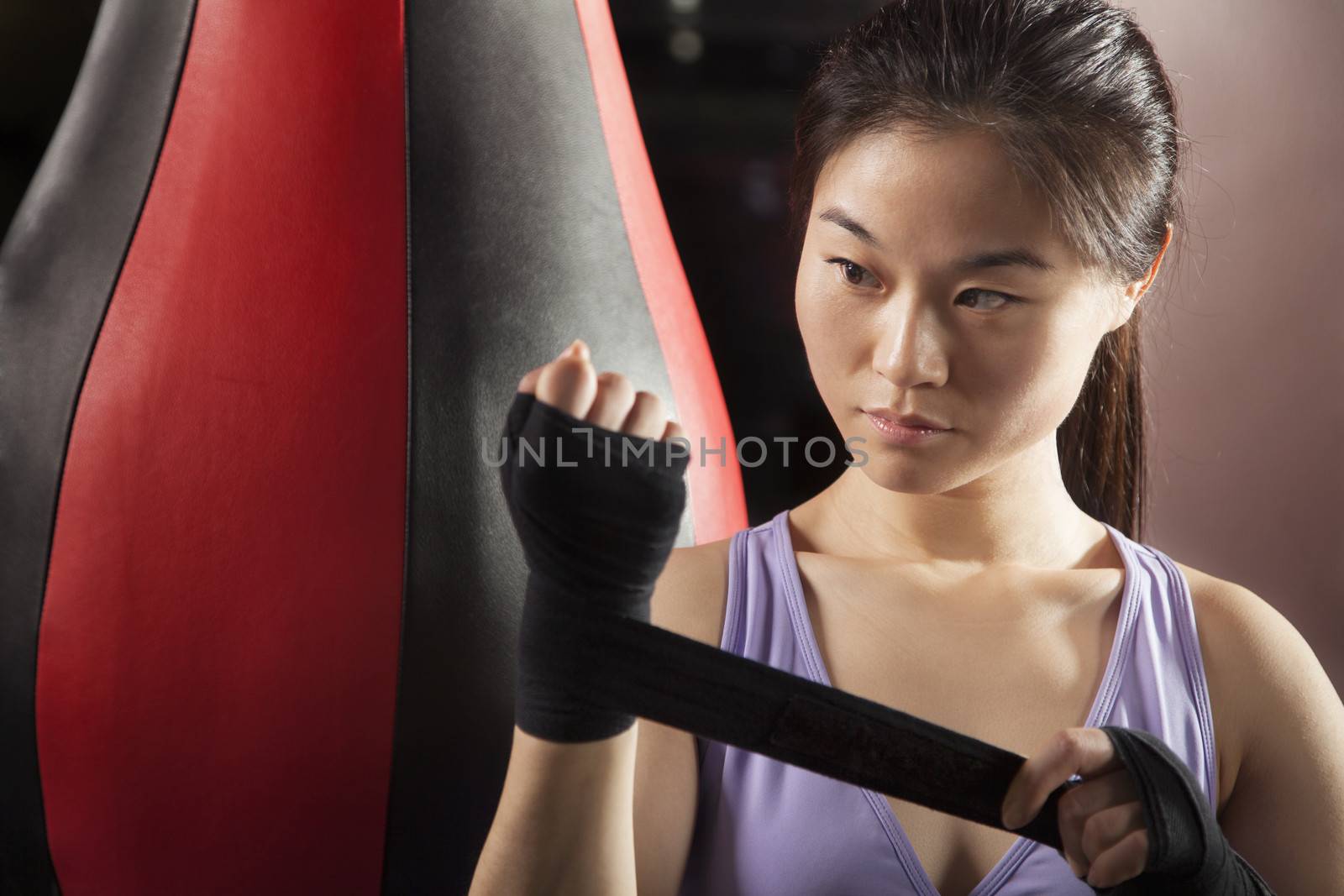 Young confident female boxer wrapper her wrists in the gym 