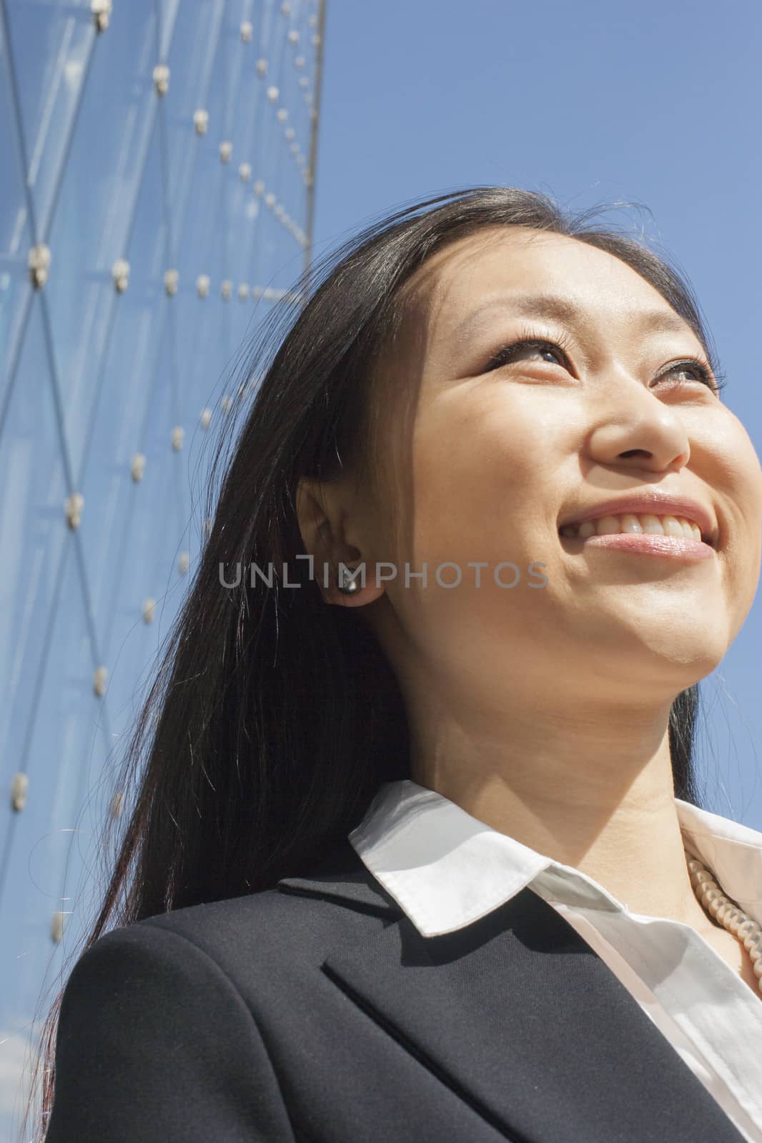 Young smiling businesswoman outside in front of glass building, close-up by XiXinXing
