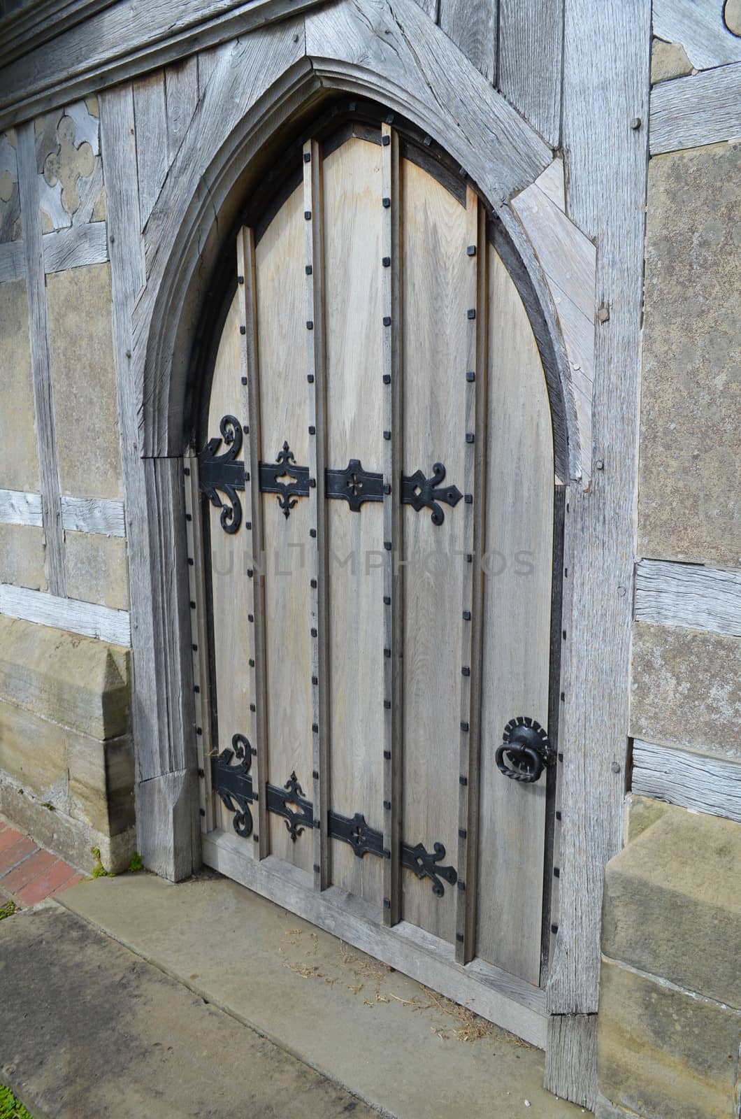 Ancient solid oak door set in a stone arch frame on a 13th century church in England.