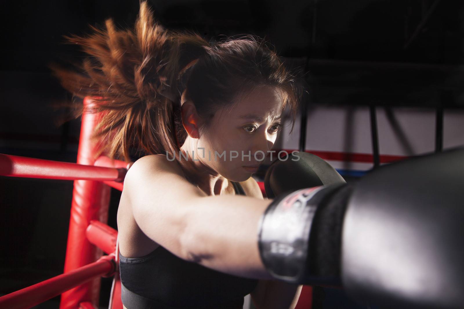 Close up of female boxer throwing a punch, hair in motion  by XiXinXing