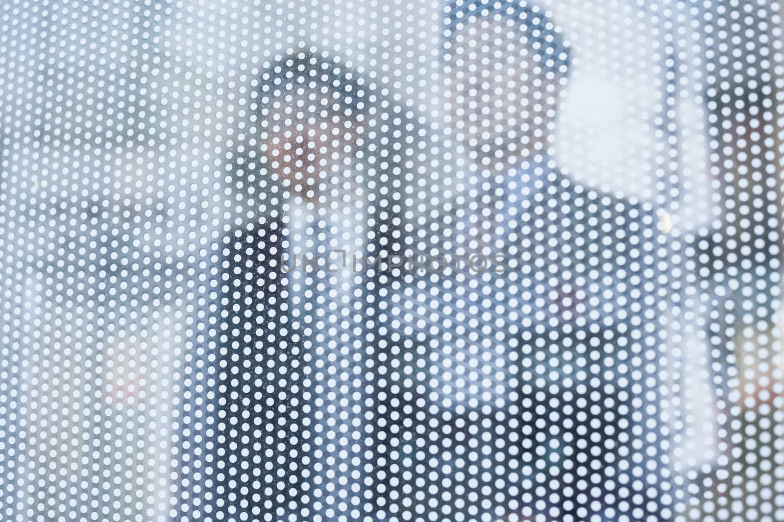 Two businessmen behind a glass wall looking out, unrecognizable faces