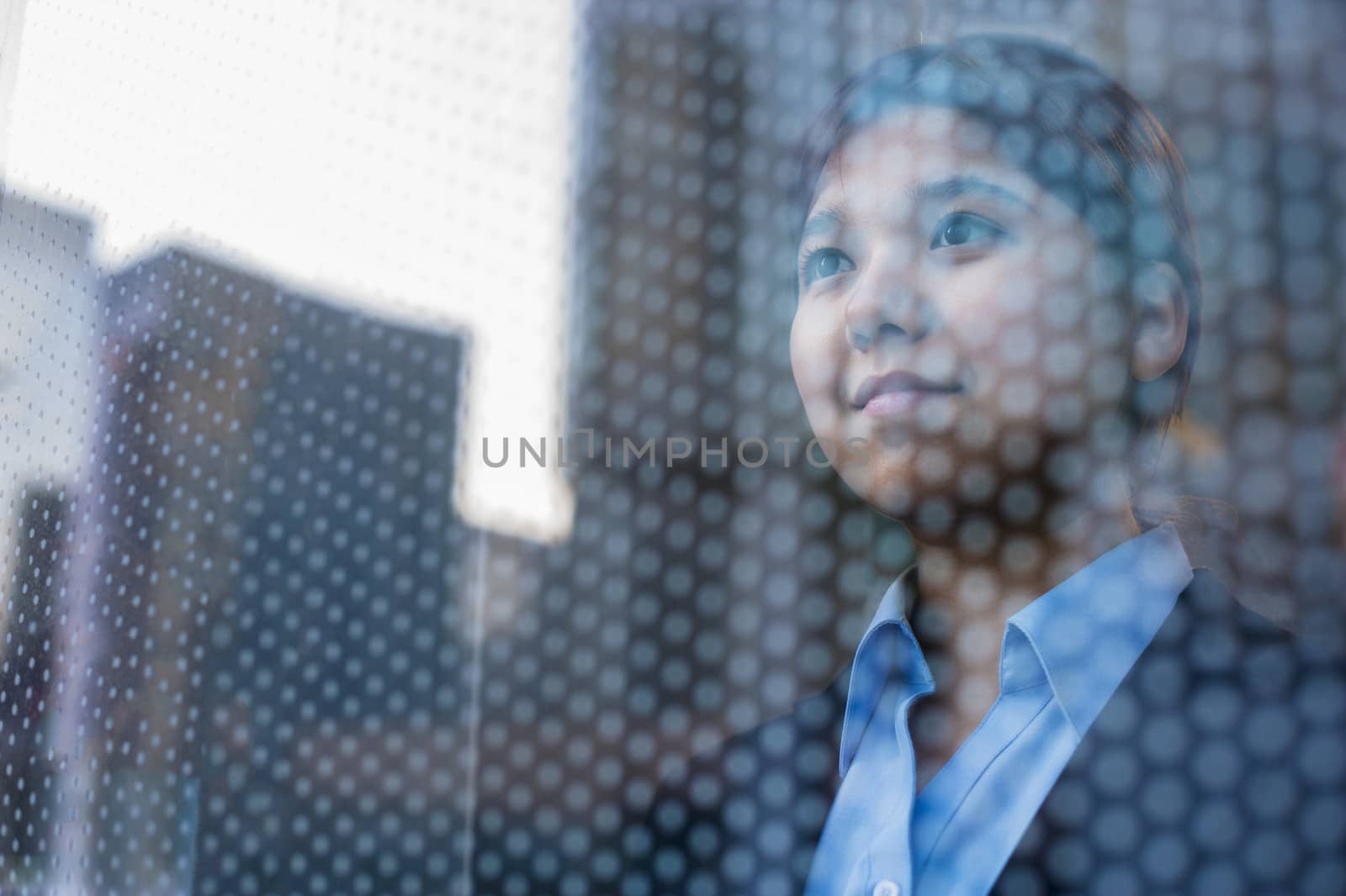 Businesswoman looking out through window, reflection of the city on the glass by XiXinXing